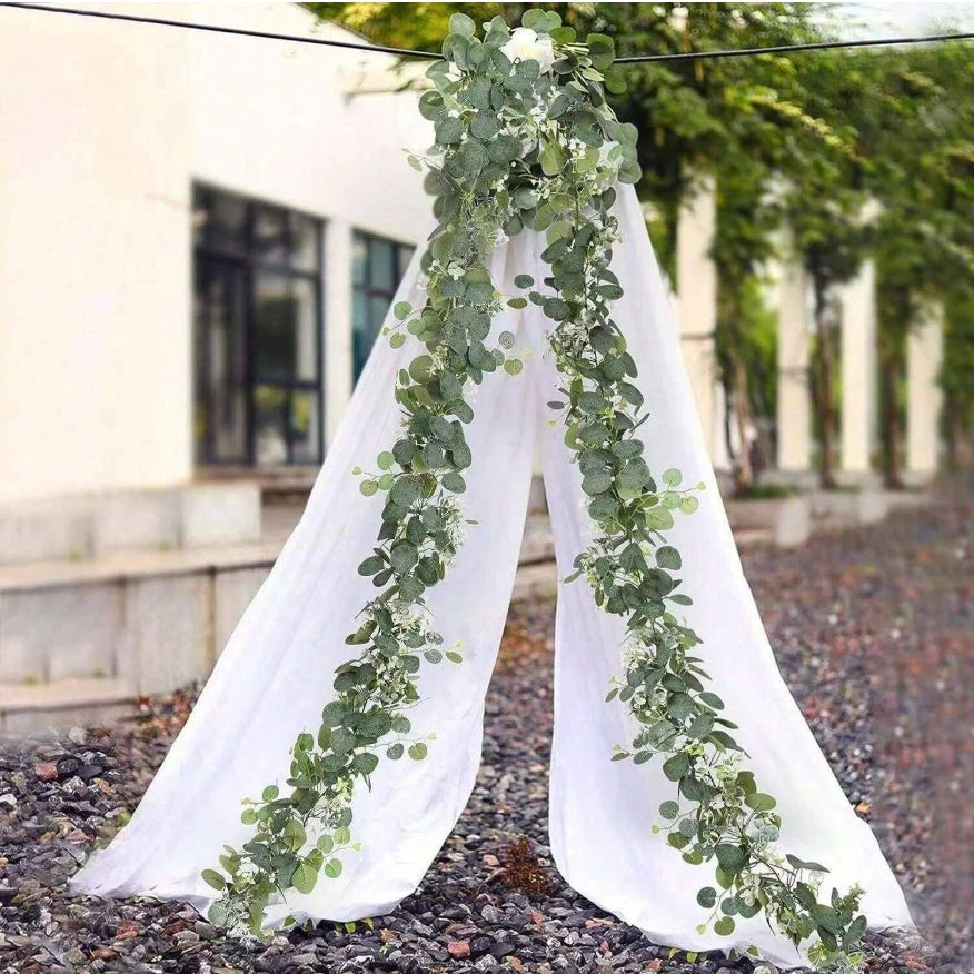 White fabric draped with a long garland of green eucalyptus leaves and white flowers for wedding decor
