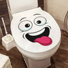 A white toilet with a funny cartoon face sticker on the tank.