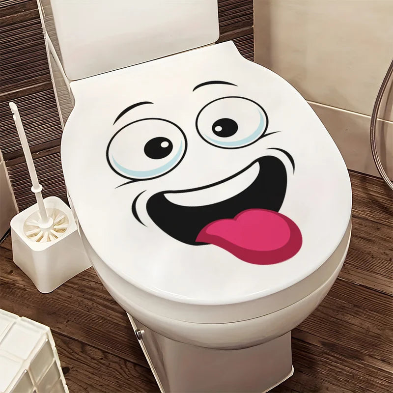 A white toilet with a funny cartoon face sticker on the tank.