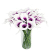A bouquet of six artificial calla lilies with white and purple markings in a clear glass vase.