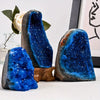 Three tumbled Bohemian blue crystal clusters displaying deep blue and purple hues on a white surface.