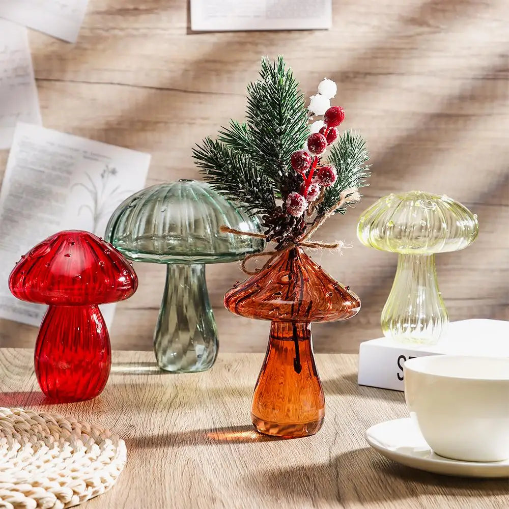 A still life featuring three mushroom-shaped glass vases in translucent red, green, and amber tones on a wooden surface.