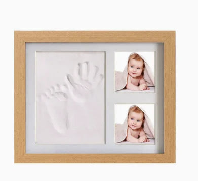 A wooden frame displaying a baby handprint and footprint keepsake inside.