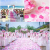 Pink silk rose petals scattered on a white aisle for an event decoration setup.