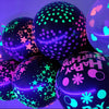 A close-up of several neon glow-in-the-dark latex balloons in purple and green with various confetti patterns.