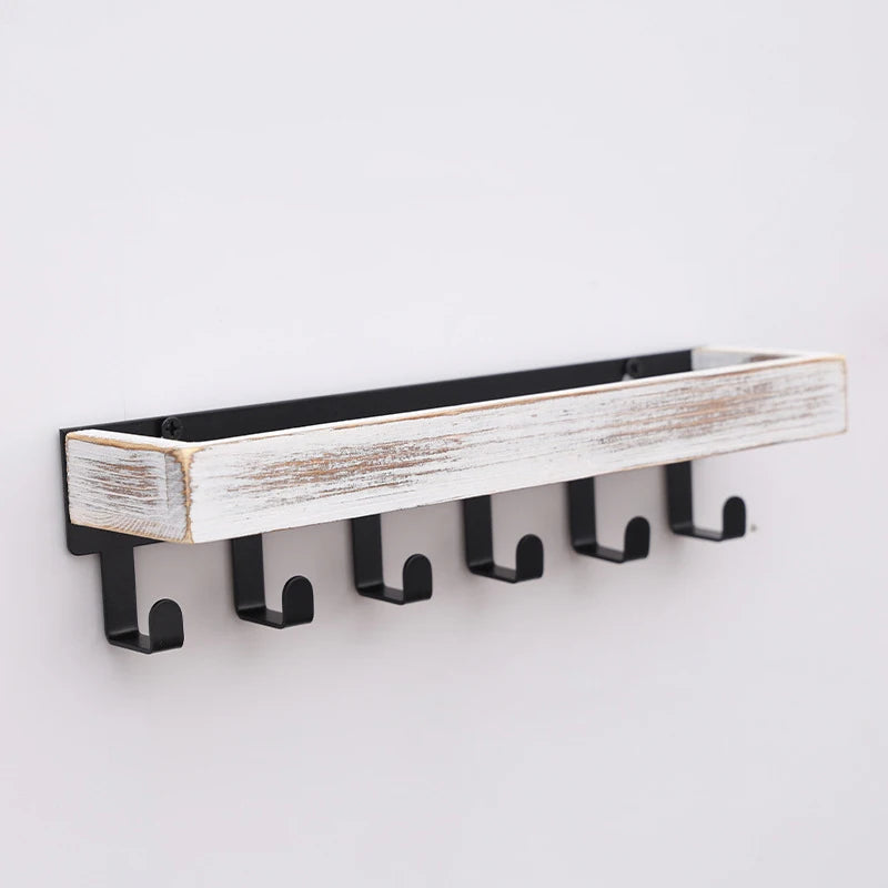 A rustic wooden floating shelf with hooks featuring distressed white and natural wood planks.