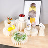 A decorative buffet riser set featuring a white cake, a bottle of Malibu liquor, and a geometric art print on a wooden table.