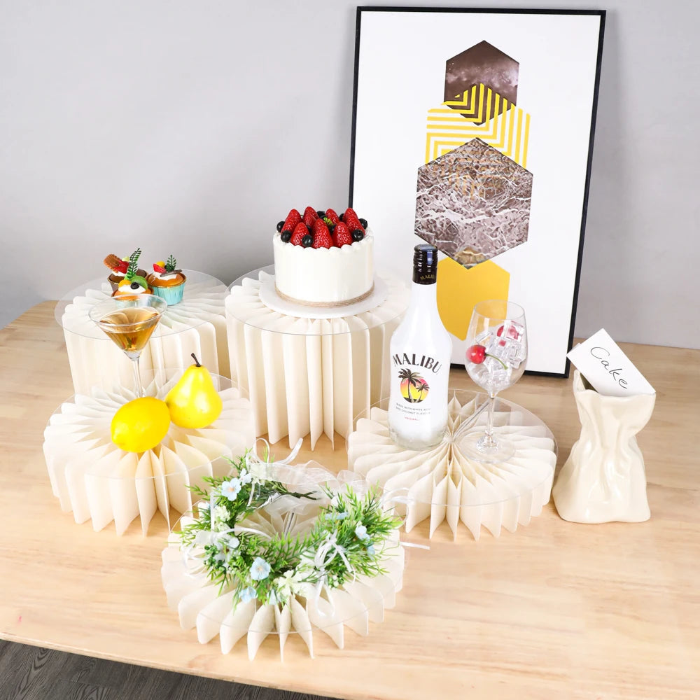 A decorative buffet riser set featuring a white cake, a bottle of Malibu liquor, and a geometric art print on a wooden table.