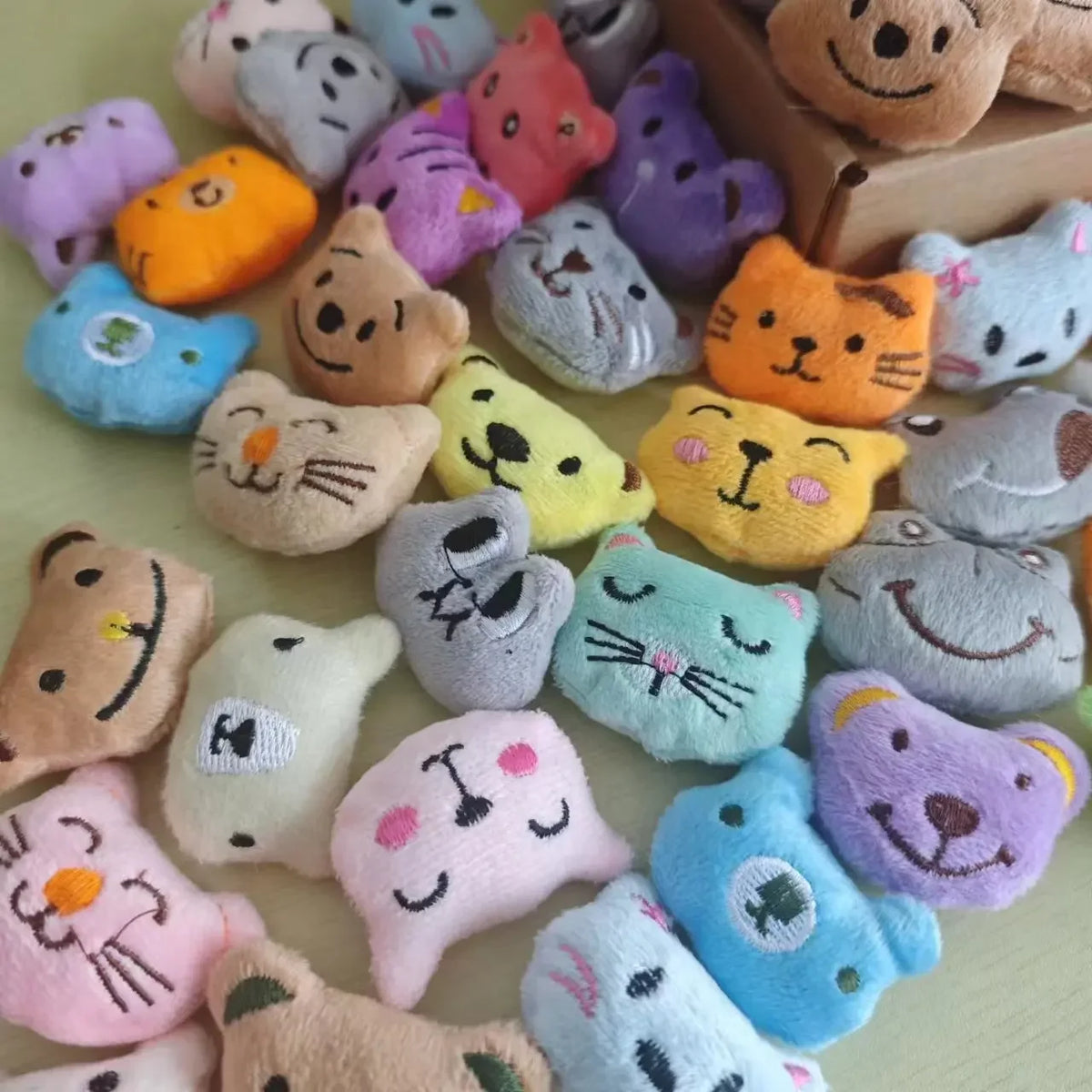 A collection of small, soft plush dolls resembling cats and other animals in various pastel colors.