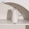 A white ceramic bud vase with vertical ridges is displayed on a shelf, showing its height and diameter.