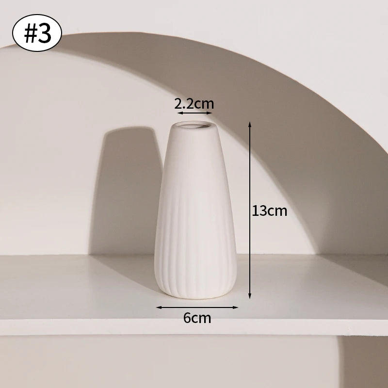 A white ceramic bud vase with vertical ridges is displayed on a shelf, showing its height and diameter.
