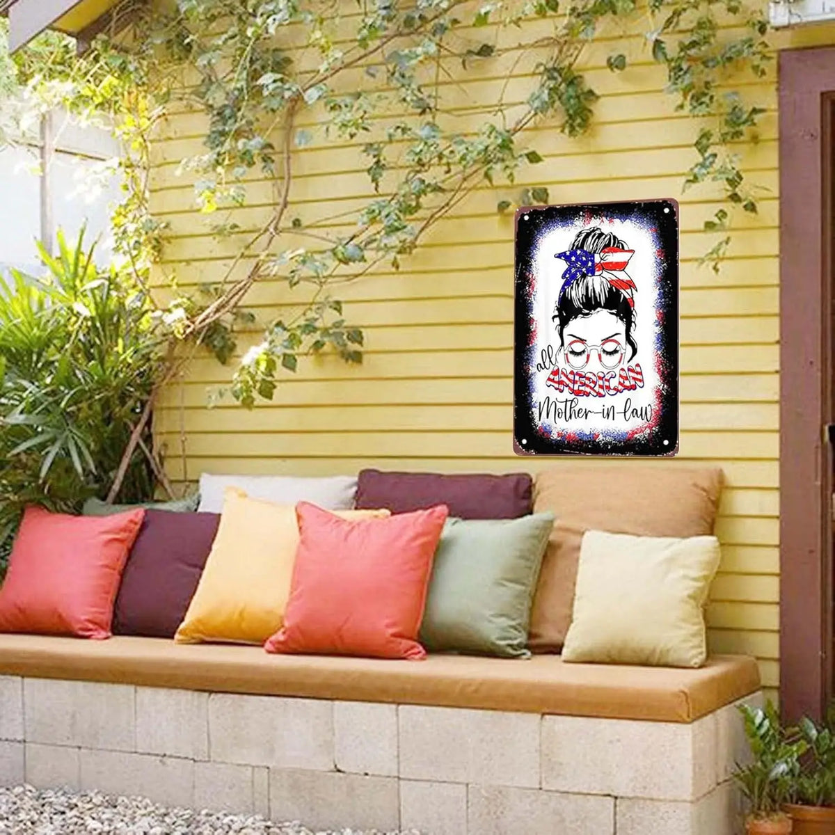A vintage metal sign featuring a silhouette of a woman's face with a crown and roses, displayed on a yellow wall.
