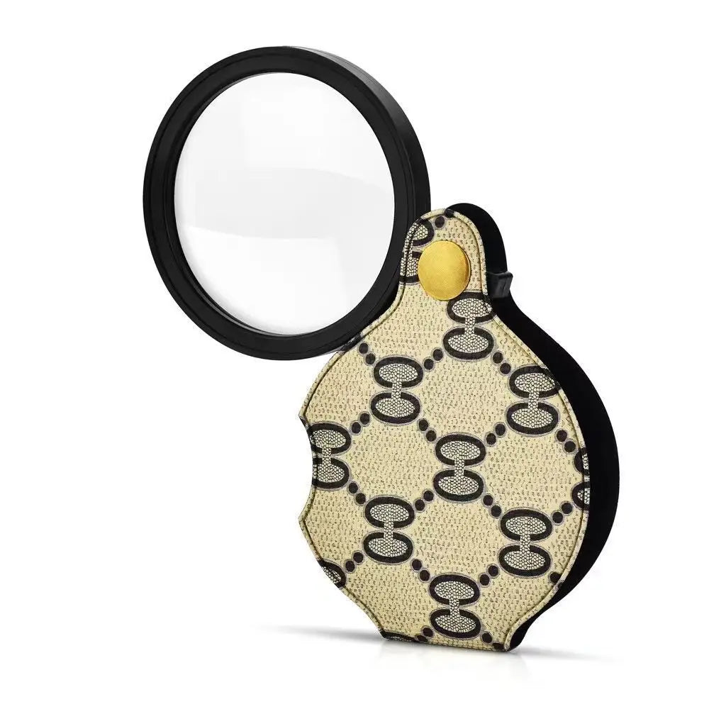 A round magnifying lens with a black frame and a beige patterned leather case attached to a keychain.