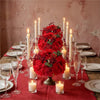 A centerpiece featuring a silk champagne rose and hydrangea flower ball surrounded by tall candles on a wooden table.
