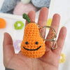 Handmade orange knitted plush toy shaped like a carrot with a green stem and gold jewelry findings