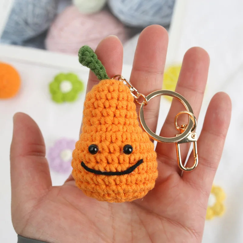 Handmade orange knitted plush toy shaped like a carrot with a green stem and gold jewelry findings