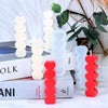 A set of two heart-shaped silicone candle molds in white and red are displayed on a white surface.