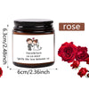 A dark glass jar candle labeled Daniel & Canla with a rose theme, next to fresh red roses.