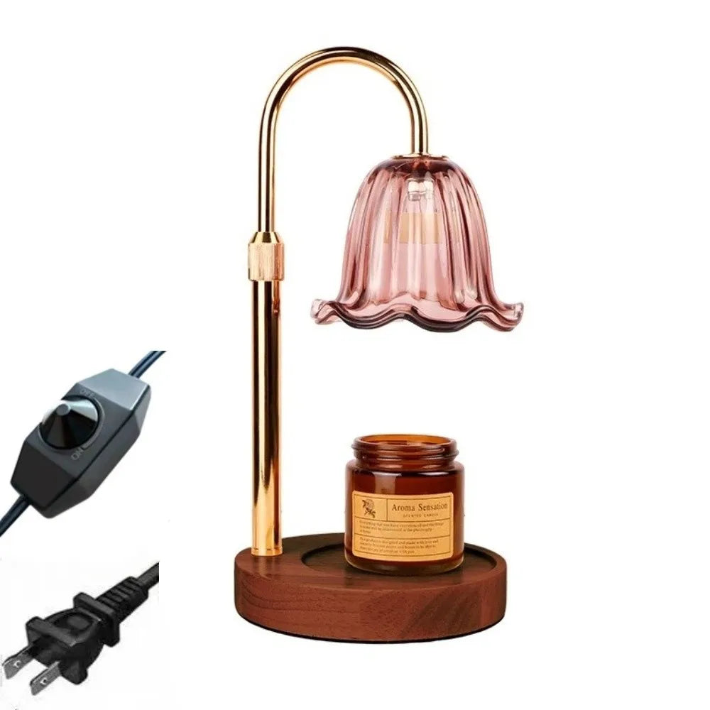 A gold-toned adjustable height aromatherapy candle warmer lamp with a pink glass shade and a wooden base.