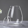 A clear, multi-size glass decor vase is shown on a gray surface with light reflections.