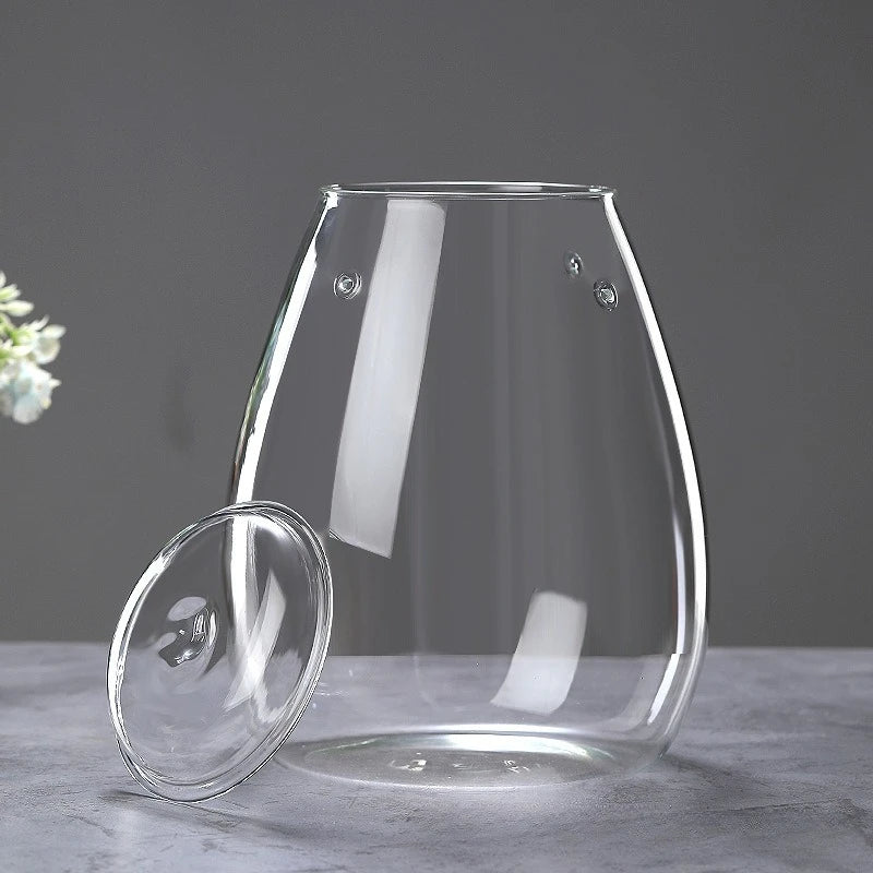 A clear, multi-size glass decor vase is shown on a gray surface with light reflections.