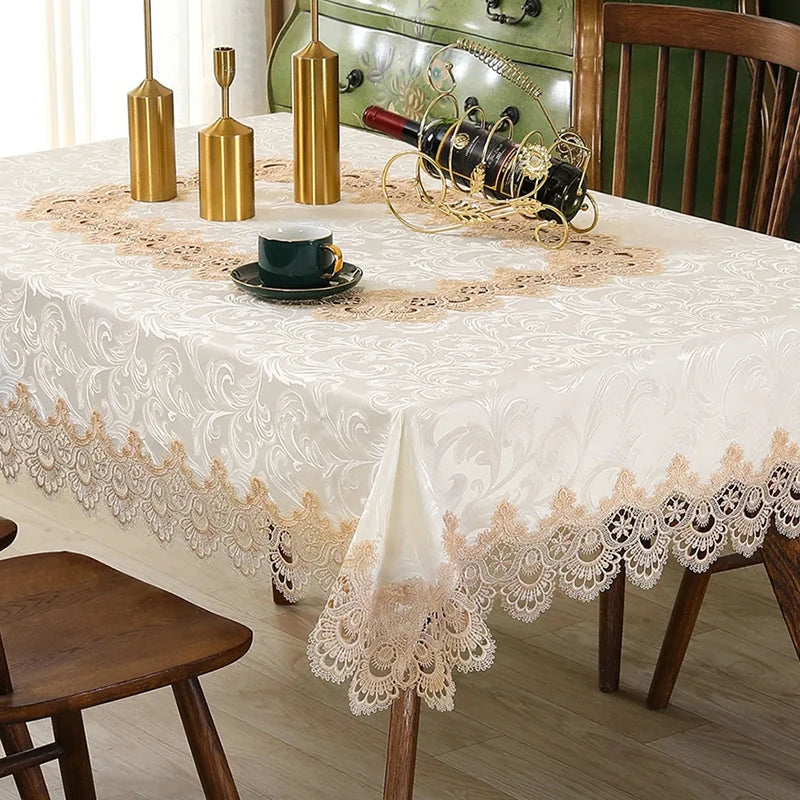 A white embroidered lace tablecloth is set on a wooden table with gold-colored decanters and a bottle.