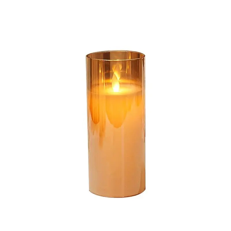 A tall, cylindrical glass pillar candle in a warm amber tone, illuminated by a flame inside.