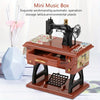 A dark brown vintage clockwork music box with a brass mechanism and storage lattice sits on a wooden stand.