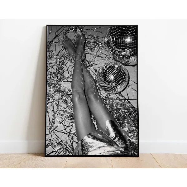 Black and white photograph of legs wearing metallic shoes and a sparkling mesh garment against a dark background.
