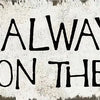 A distressed metal sign with black text that reads There's always time to sit on the porch