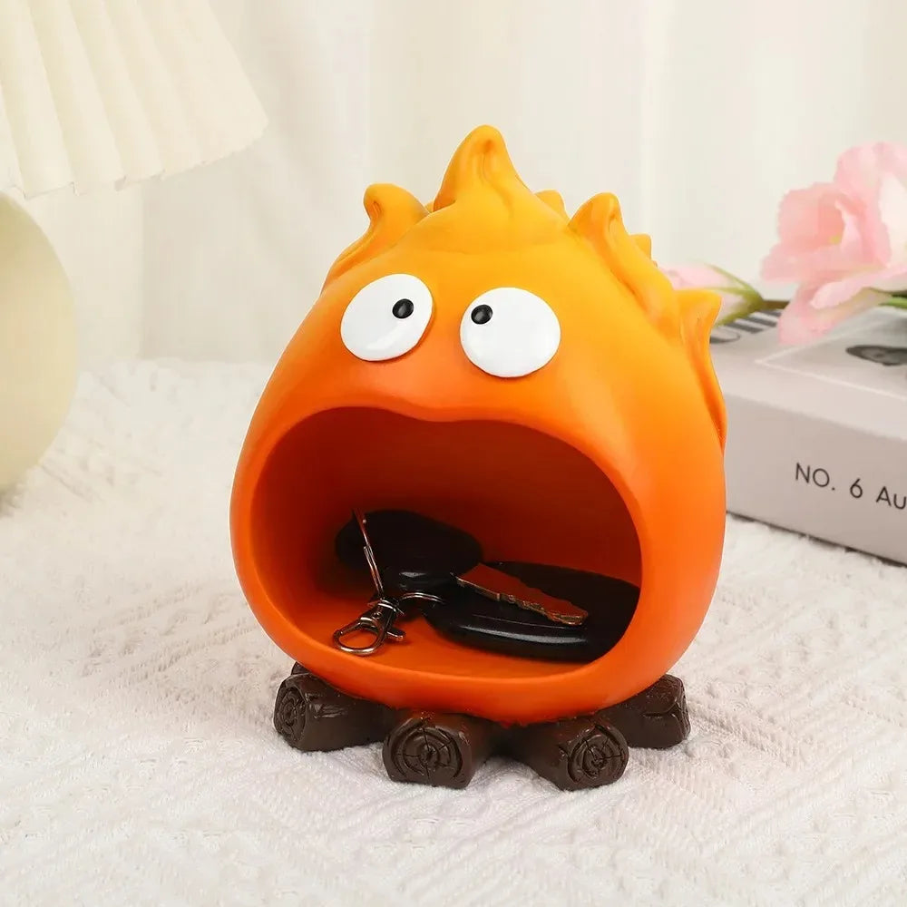 An orange resin fire spirit figurine with large eyes and an open mouth, resting on a white cloth.