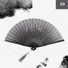 A black and white photograph of a vintage silk bamboo folding hand fan with delicate floral designs.