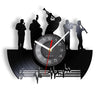 A wall clock shaped like a vinyl record featuring silhouettes of musicians and a clock face.