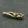 Vintage brass monkey key chain charm lying on a dark gray surface.