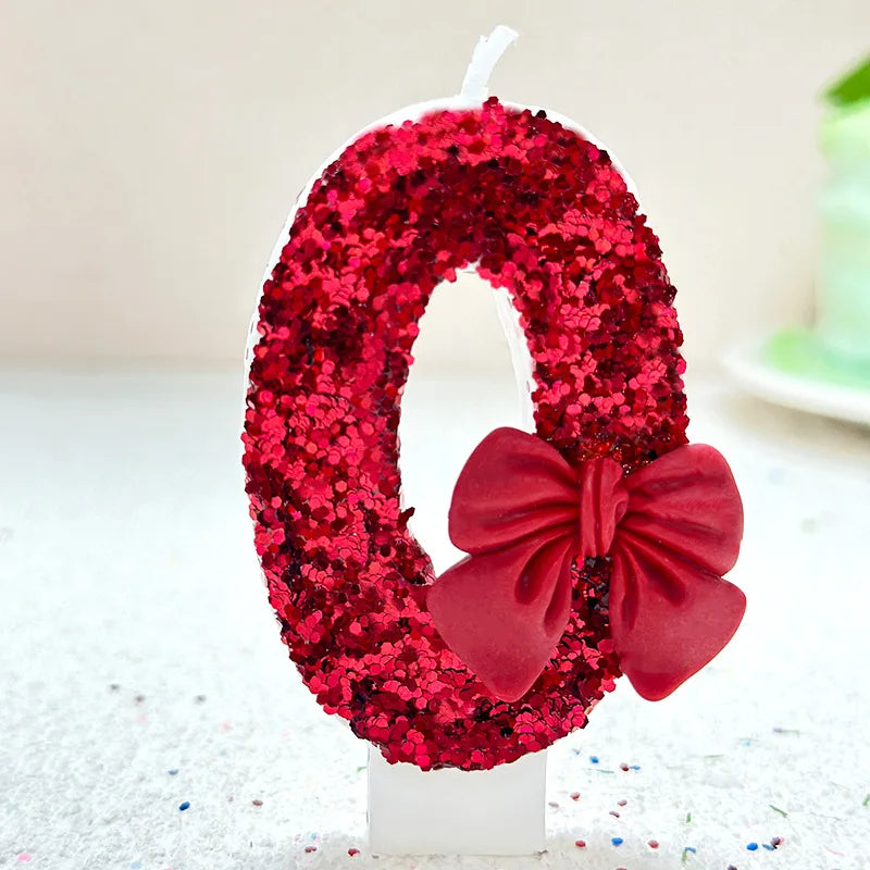 A red bow number candle decorated with red glitter and a large red satin bow.