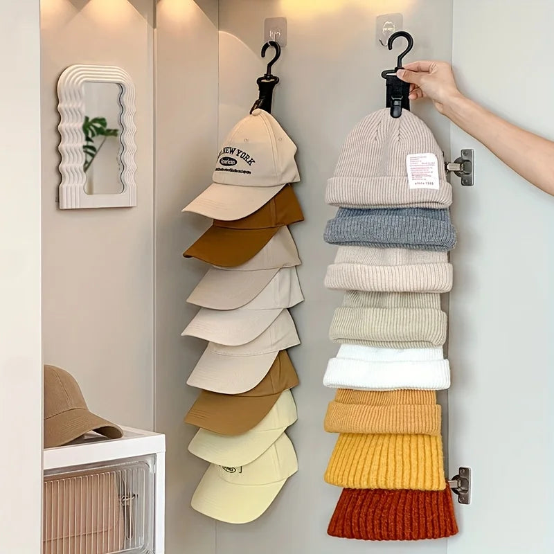 A hand hangs a stack of beige, gray, and tan hats on an organizer rack inside a closet.