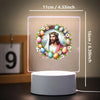 A glowing 3D LED night light featuring a wreath of flowers and eggs surrounding a depiction of Jesus Christ.