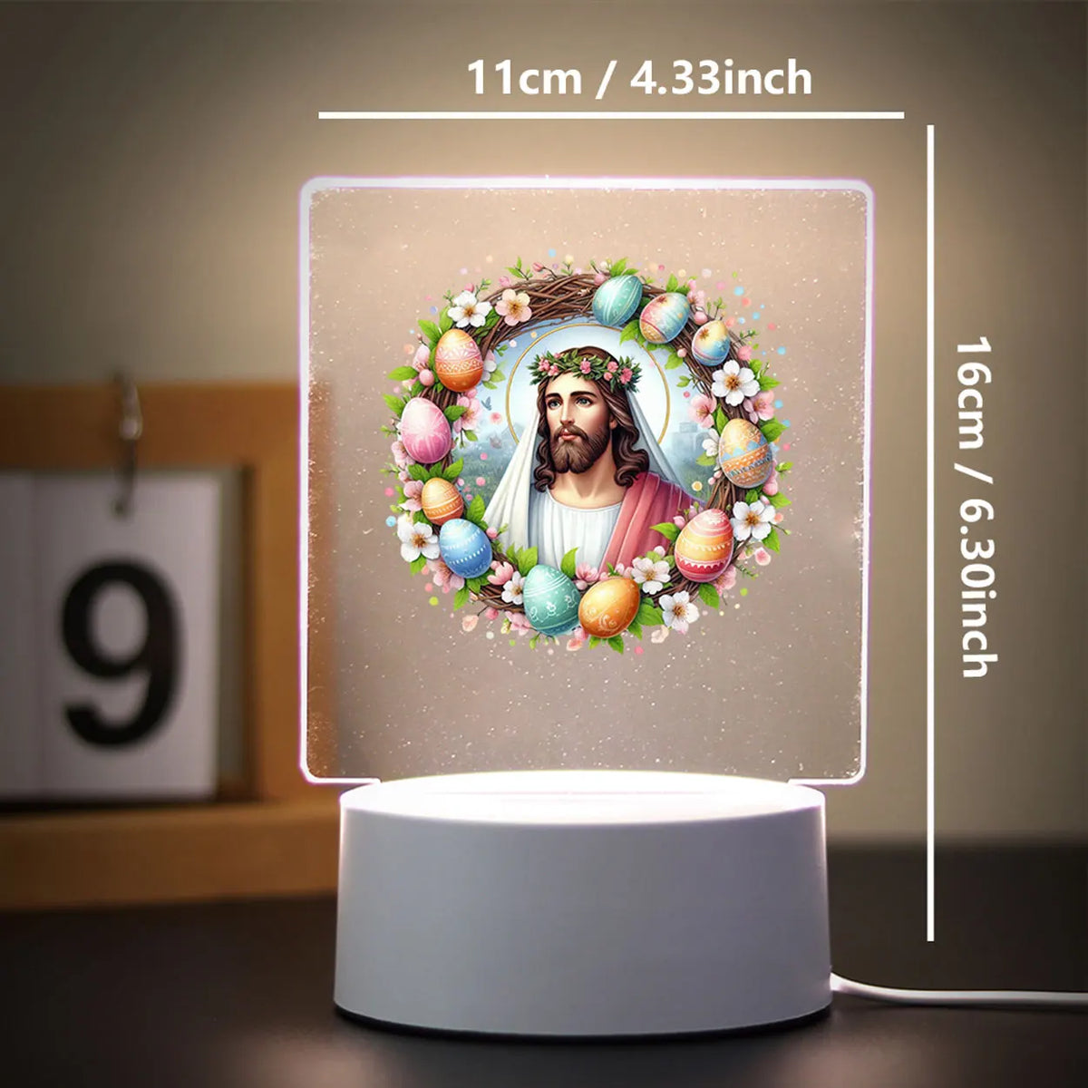 A glowing 3D LED night light featuring a wreath of flowers and eggs surrounding a depiction of Jesus Christ.