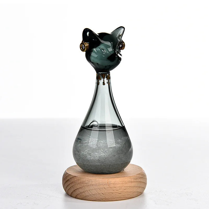A glass bottle decoration shaped like an Egyptian cat with a green body and gold accents, resting on a wooden base.