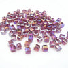 A pile of square cut glass crystal beads in shades of purple and pink for jewelry making