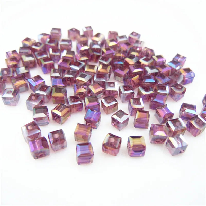 A pile of square cut glass crystal beads in shades of purple and pink for jewelry making