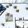 A collection of fifteen gold star-shaped fridge magnets arranged on a white surface.