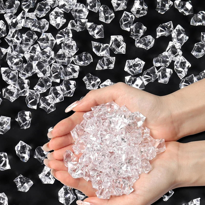 A hand holds crushed clear acrylic pebbles against a background of larger diamond-shaped crystals.