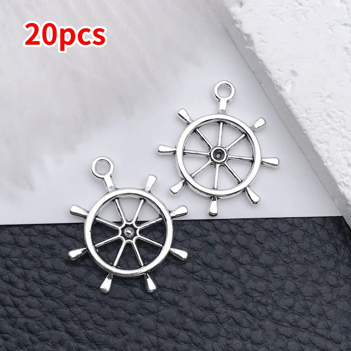 A set of 20 silver vintage ship anchor charms for jewelry making displayed on a dark surface.