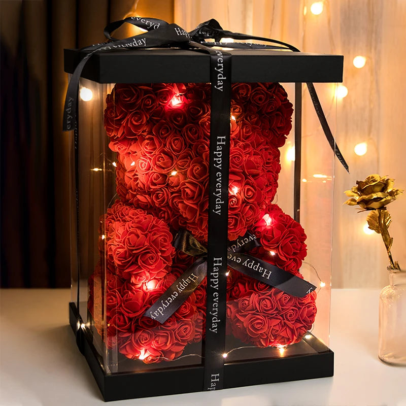 Un rosier en peluche rouge fait de tissu avec des lumières LED intégrées, exposé dans une boîte transparente.