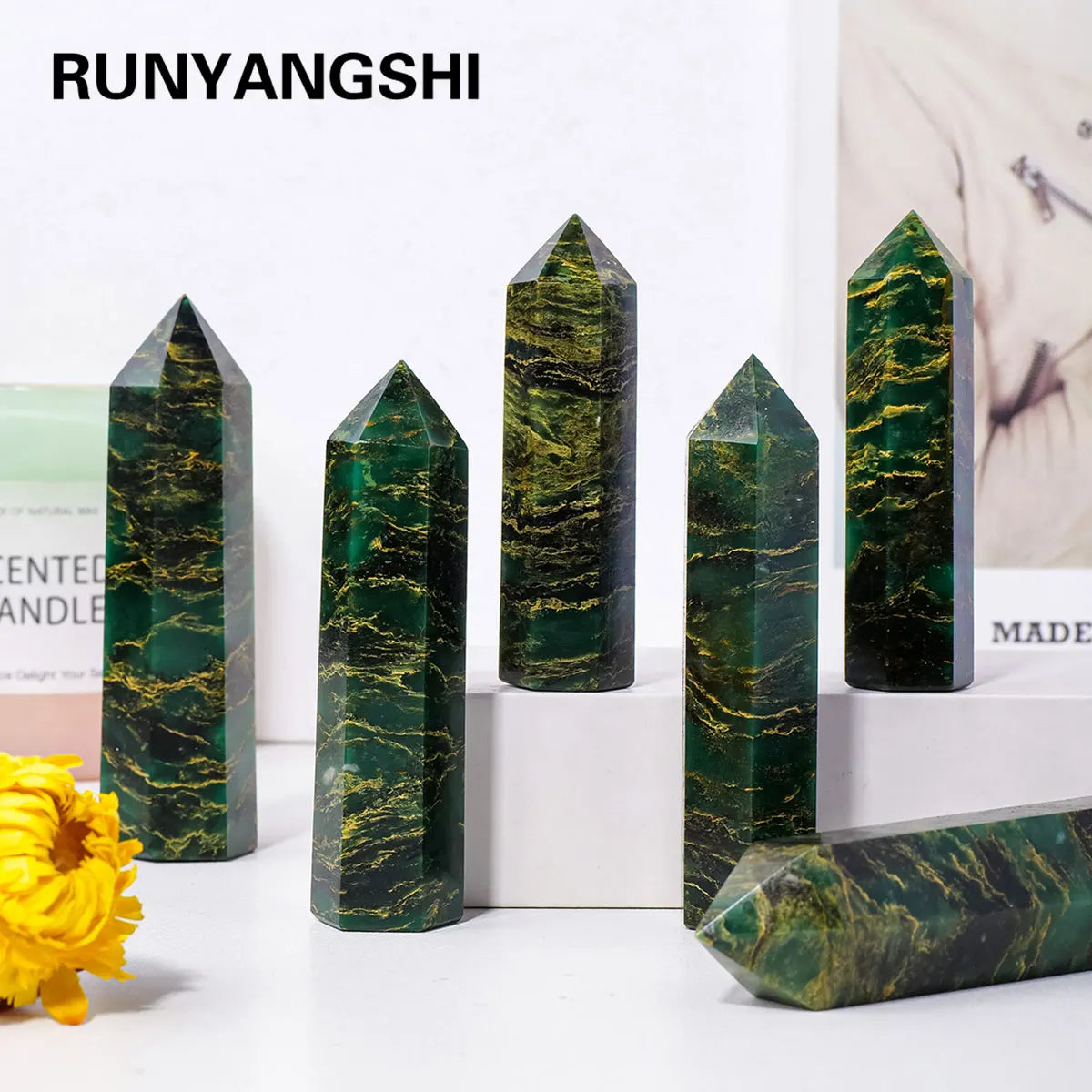 A collection of dark green emerald crystal point healing wands displayed on a white surface.