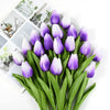 A bouquet of purple and white artificial tulips with green stems and leaves.