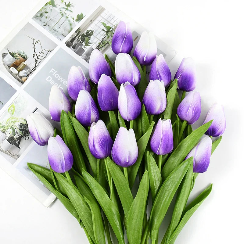 A bouquet of purple and white artificial tulips with green stems and leaves.