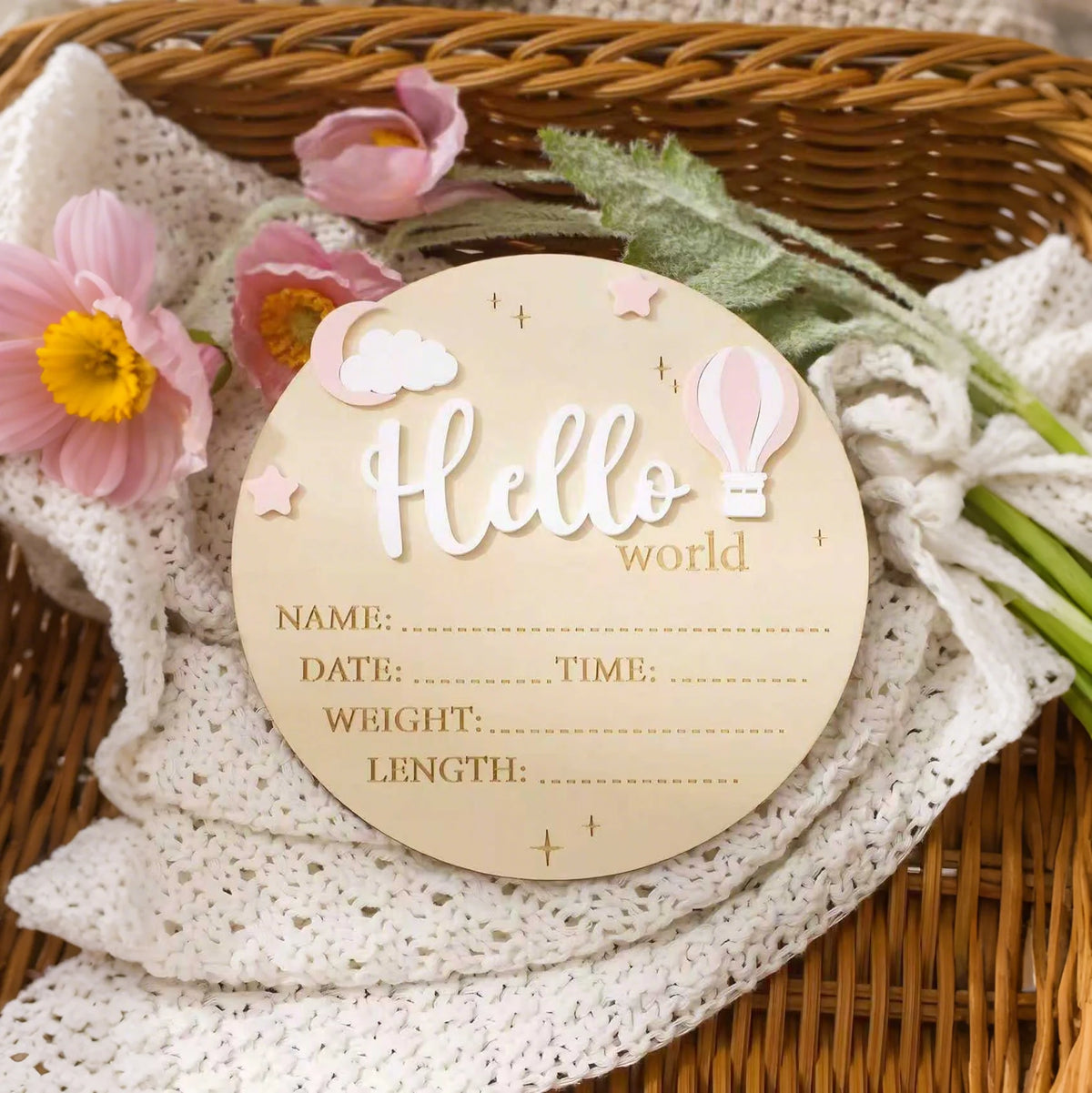 A round wooden birth announcement sign with the word Hello and fields for name date time weight and length is displayed on a 