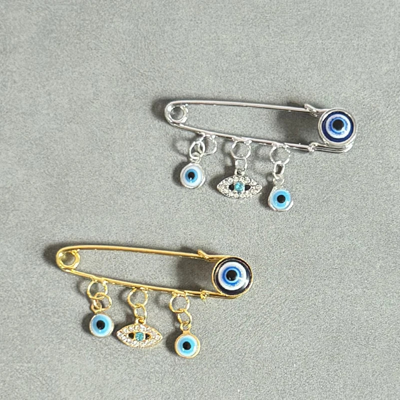 Elegant gold and silver evil eye brooch pin featuring multiple eye charms.